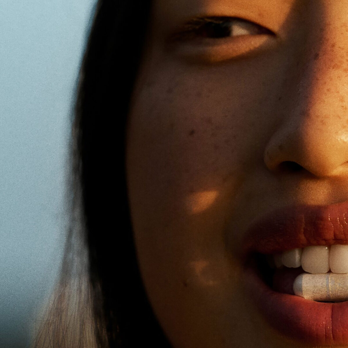 Close up of woman with vitamin between her teeth