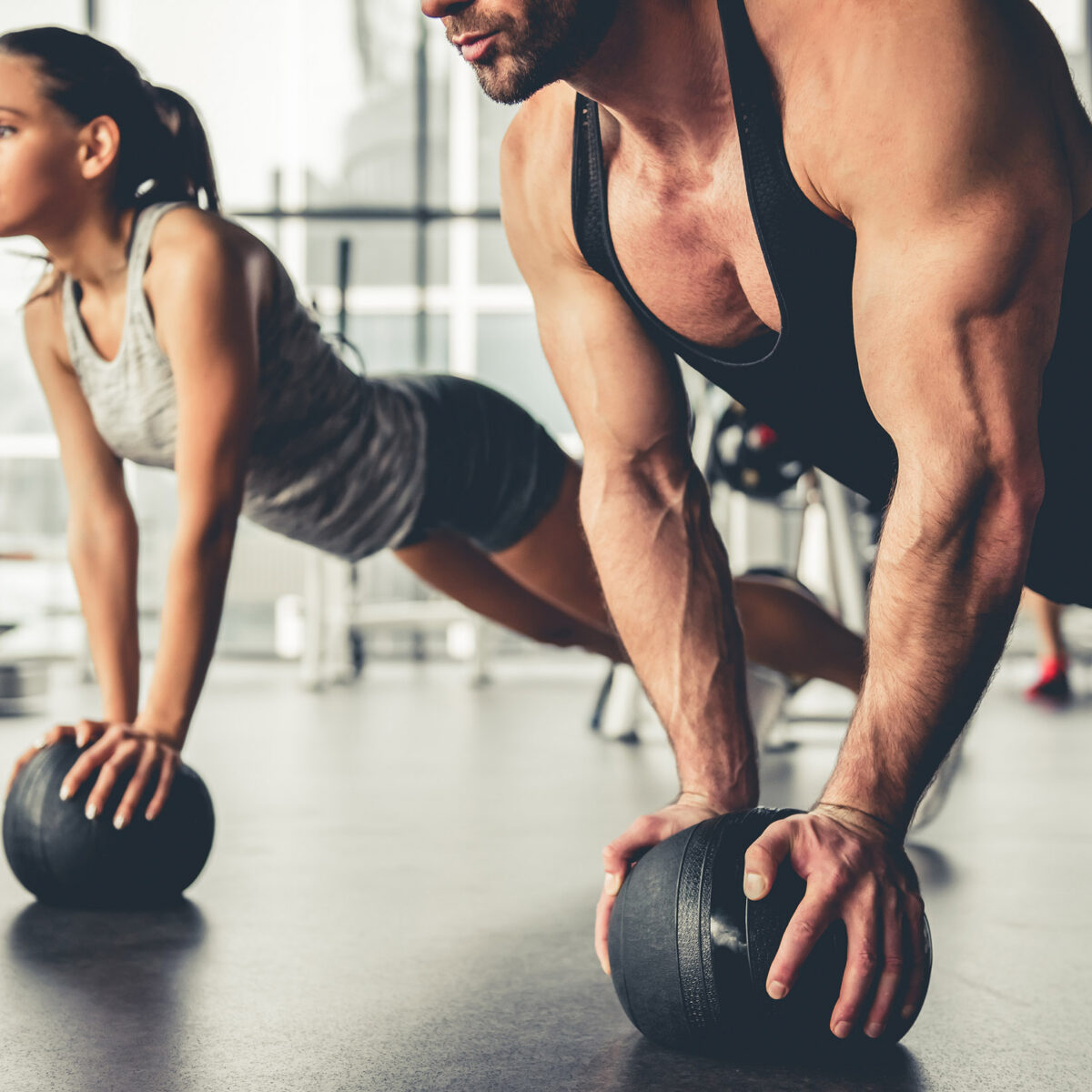Man and woman working out with weighted balls